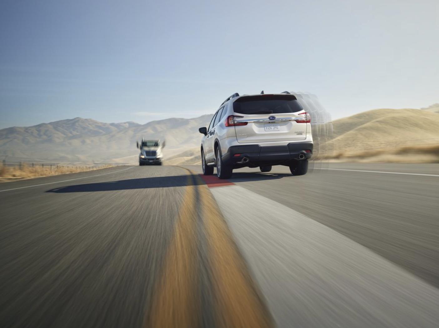 2026 Subaru Ascent in silver on an open desert highway, rear view with motion blur