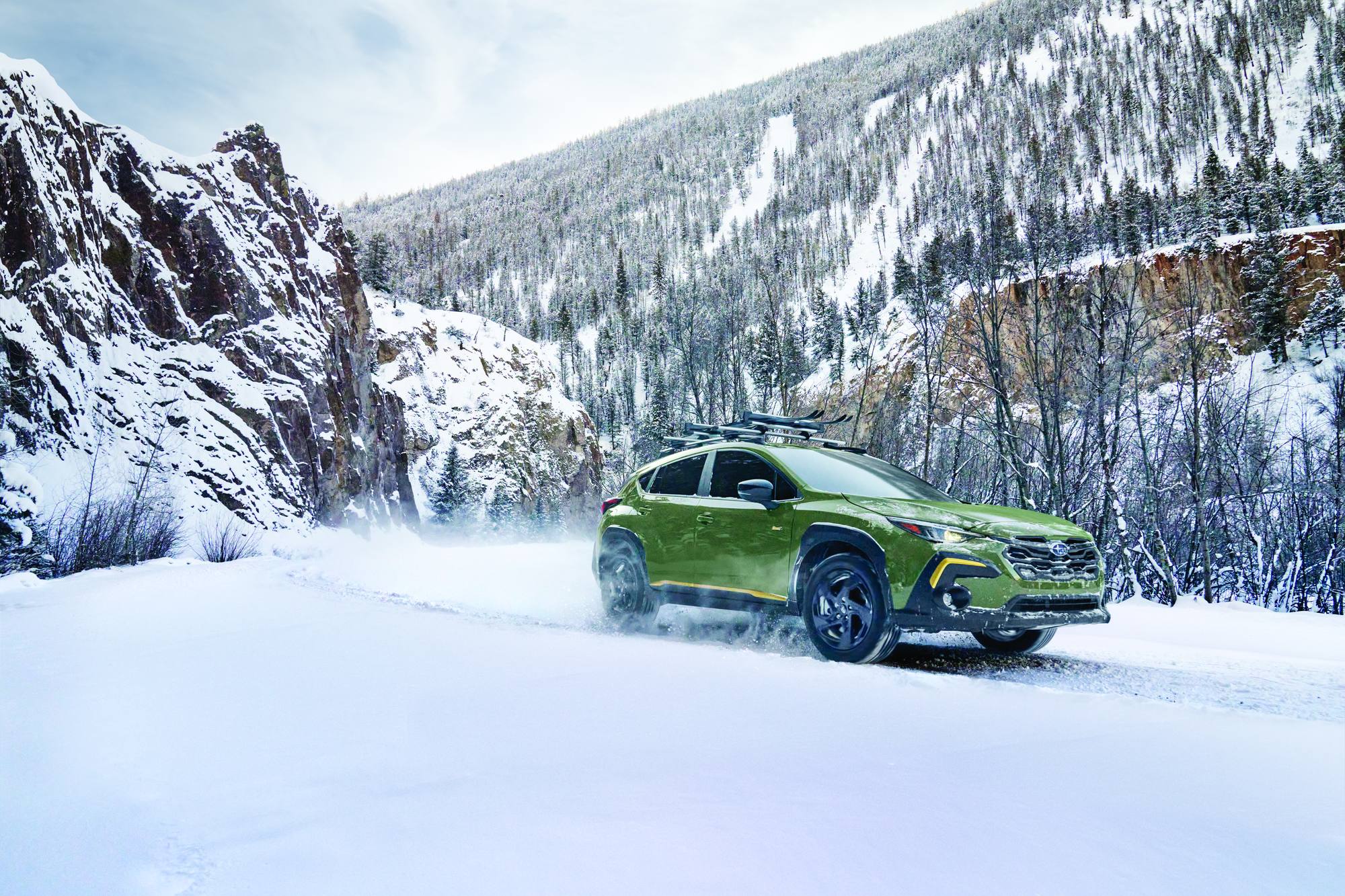 2026 Subaru Crosstrek Wilderness in green throwing snow on a canyon road