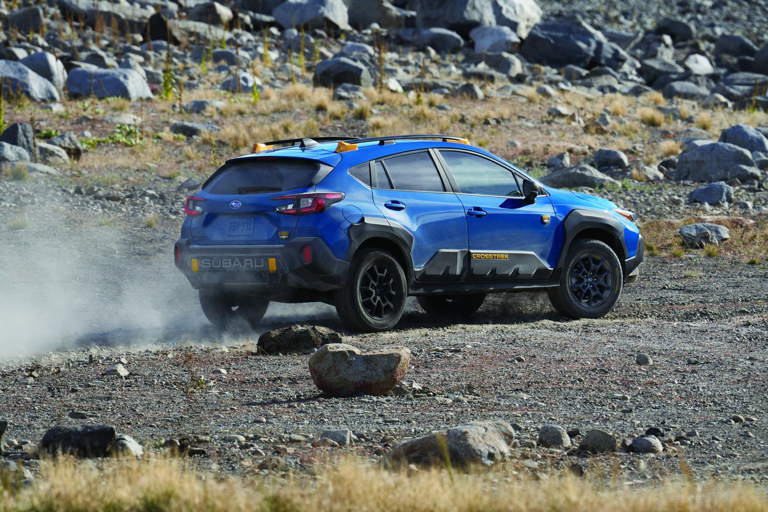 2026 Subaru Crosstrek Wilderness in blue on a rocky desert trail, rear three-quarter view
