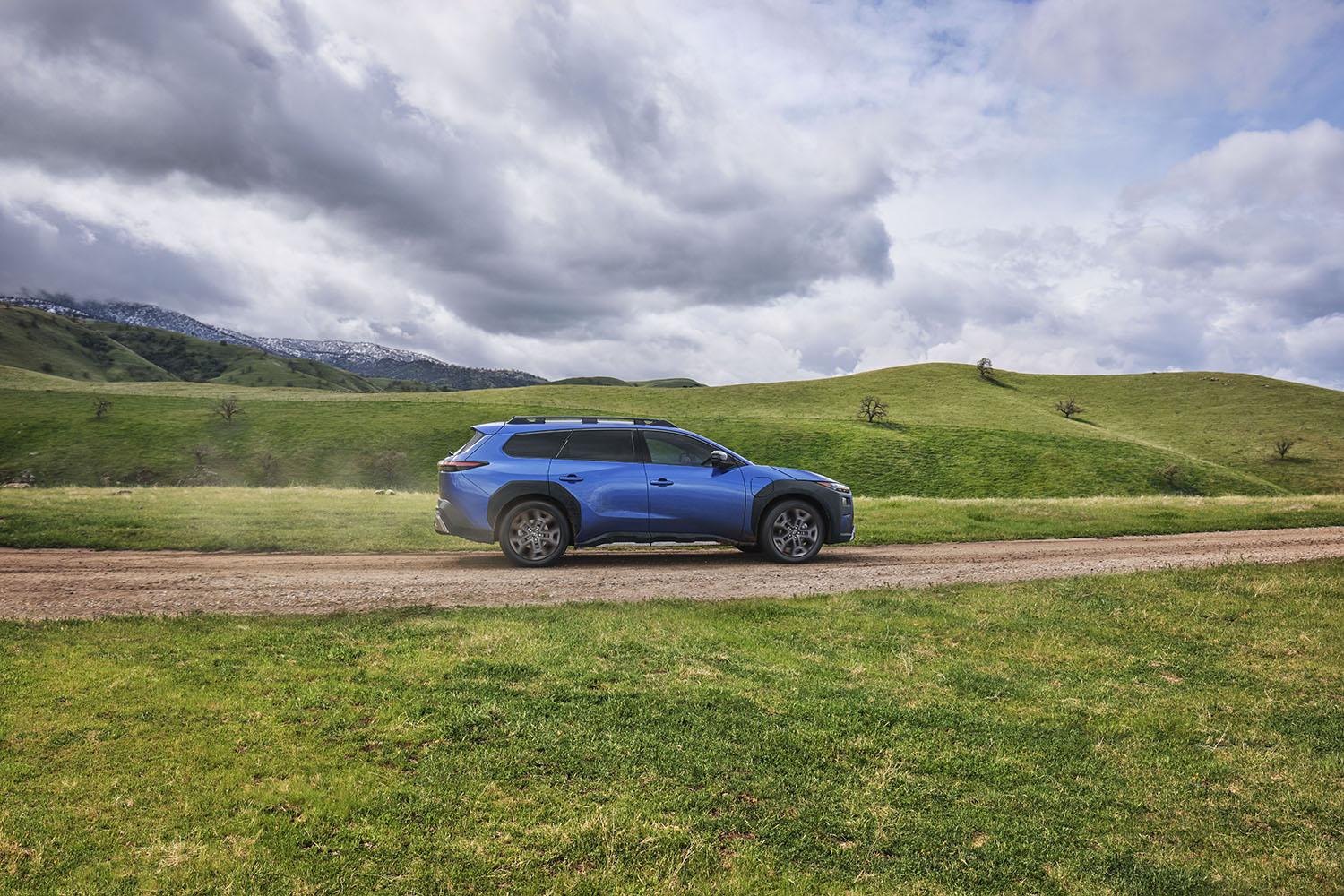 2026 Subaru Trailseeker in blue on a dirt road through green rolling hills
